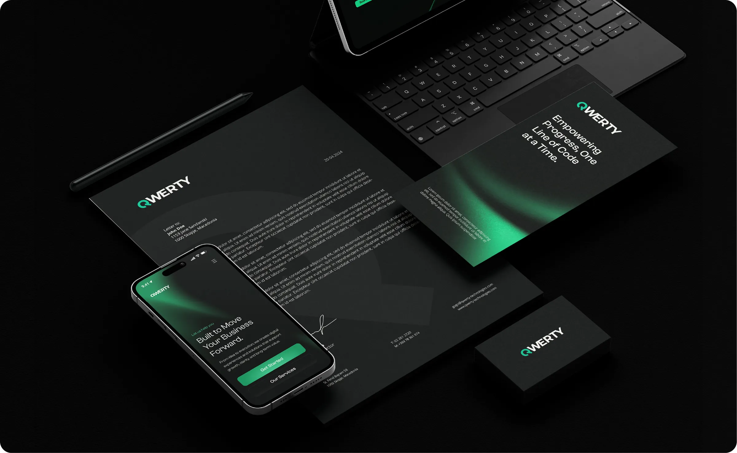 QWERTY letterhead, business card, phone and tablet laid out on a black desk