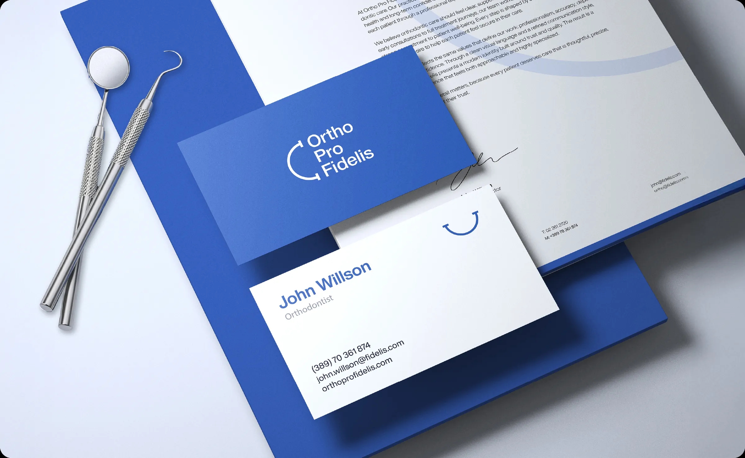 Ortho Pro Fidelis letterhead and business cards arranged with dental instruments