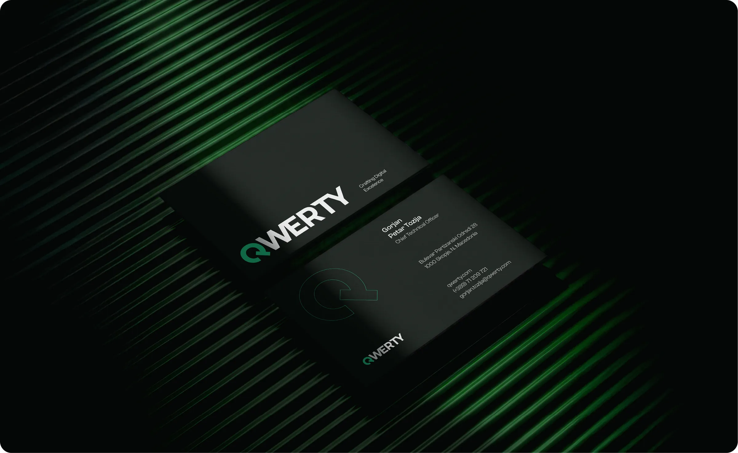 Two QWERTY business cards angled on a ridged surface lit green